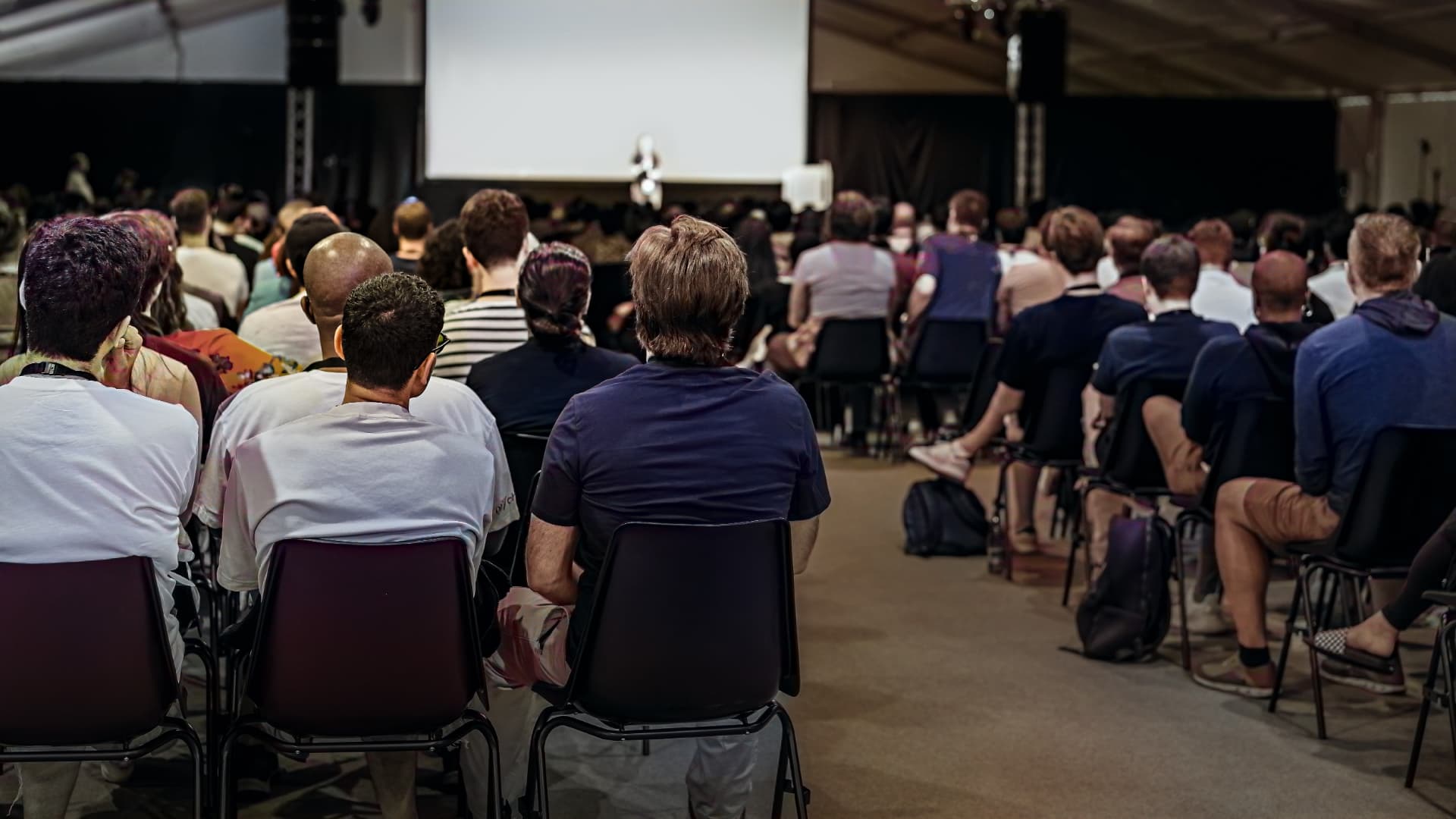 Deelnemers luisteren naar onderwijs in een conferentiezaal