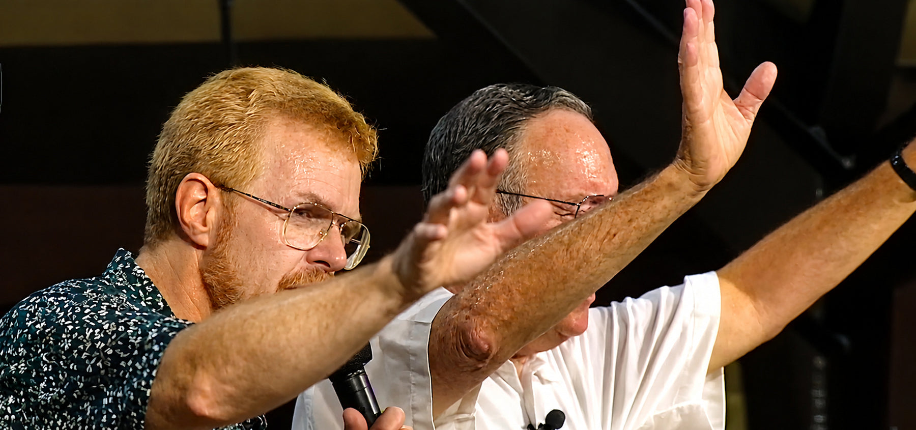 Derek Prince bidt met opgeheven hand tijdens een Herstelconferentie